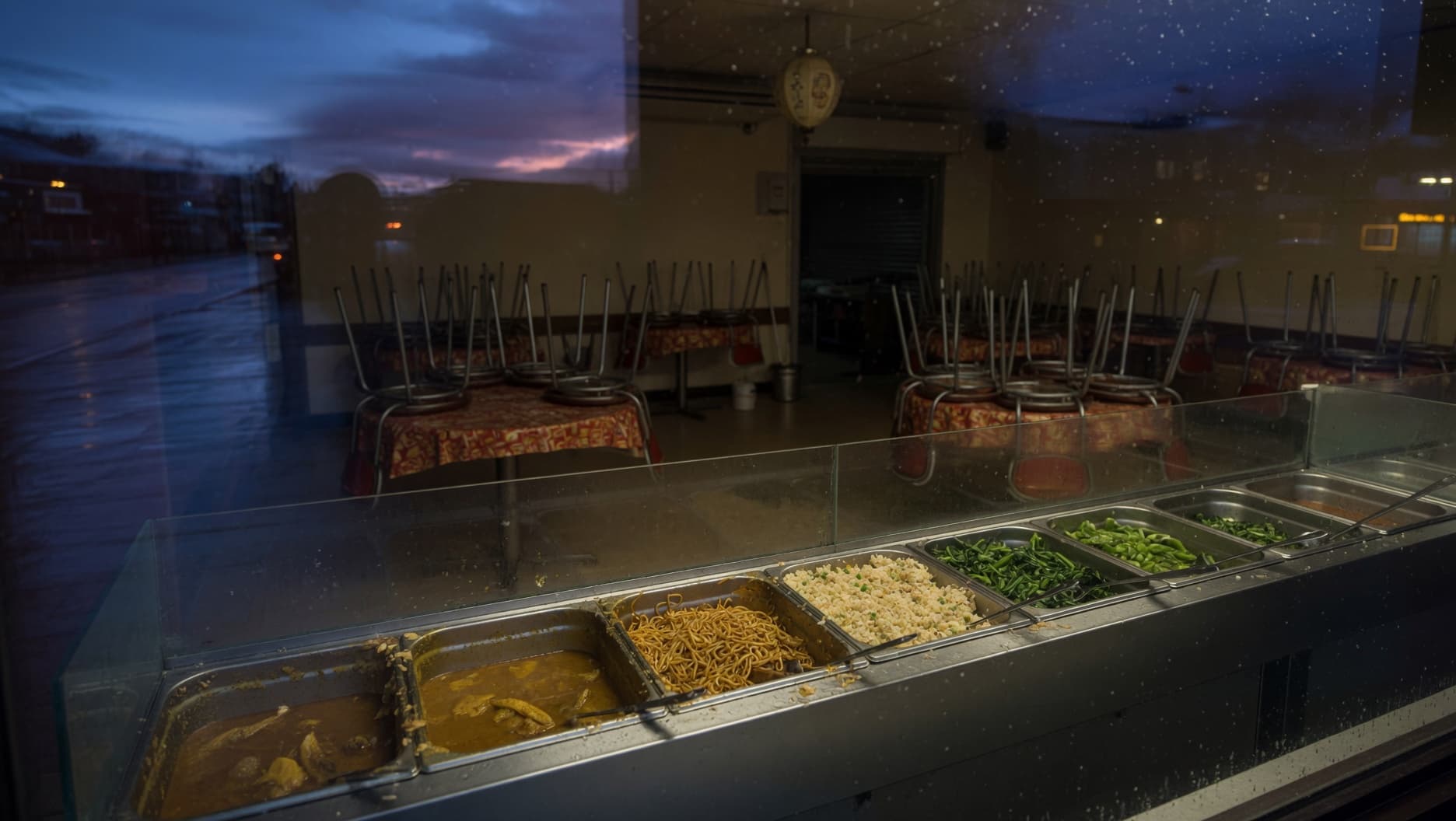 A restaurant kitchen at the end of service, with unsold trays of food